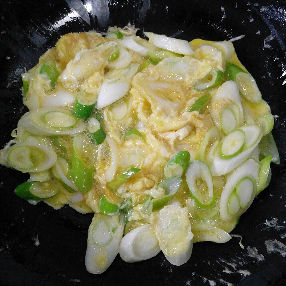 锅内油热后倒入葱花鸡蛋翻炒至蛋液凝固